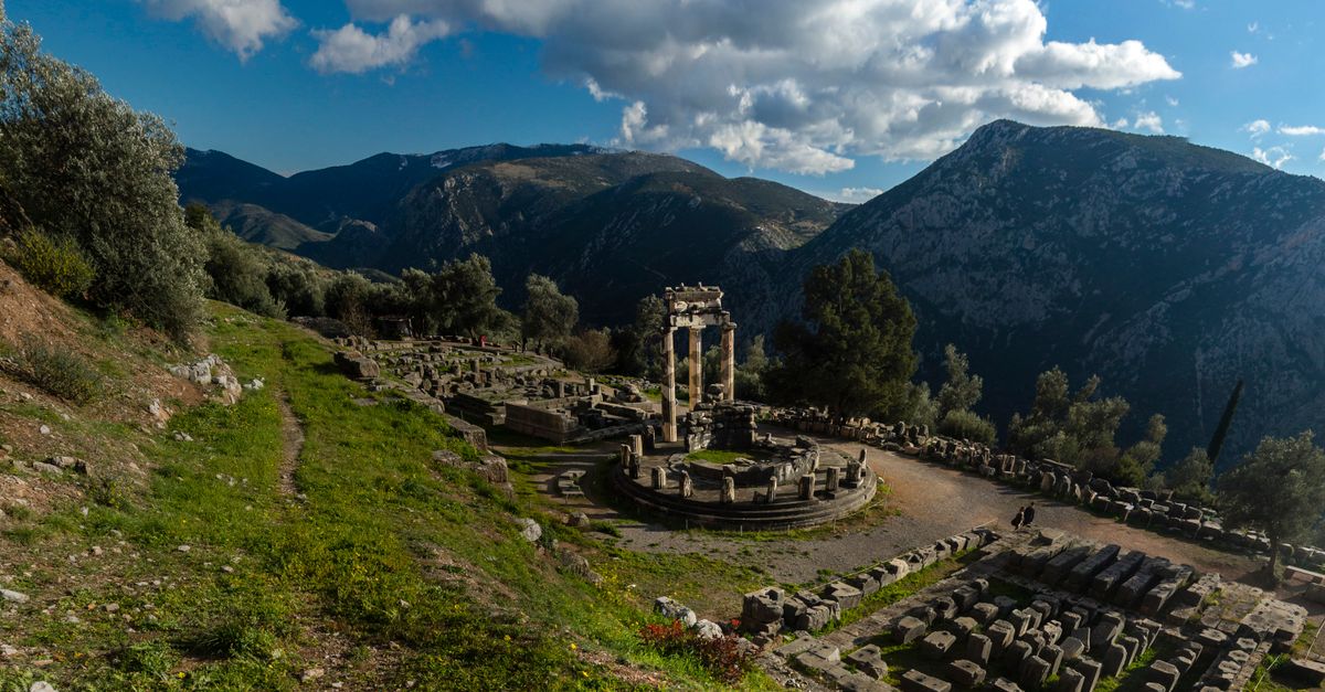 Explore the ancient ruins of Delphi, Greece, set against a stunning mountain landscape under a vibrant blue sky.